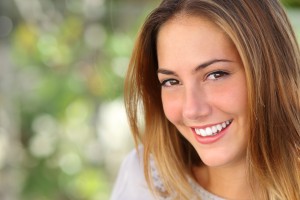 Beautiful woman with a whiten perfect smile outdoor with a green background